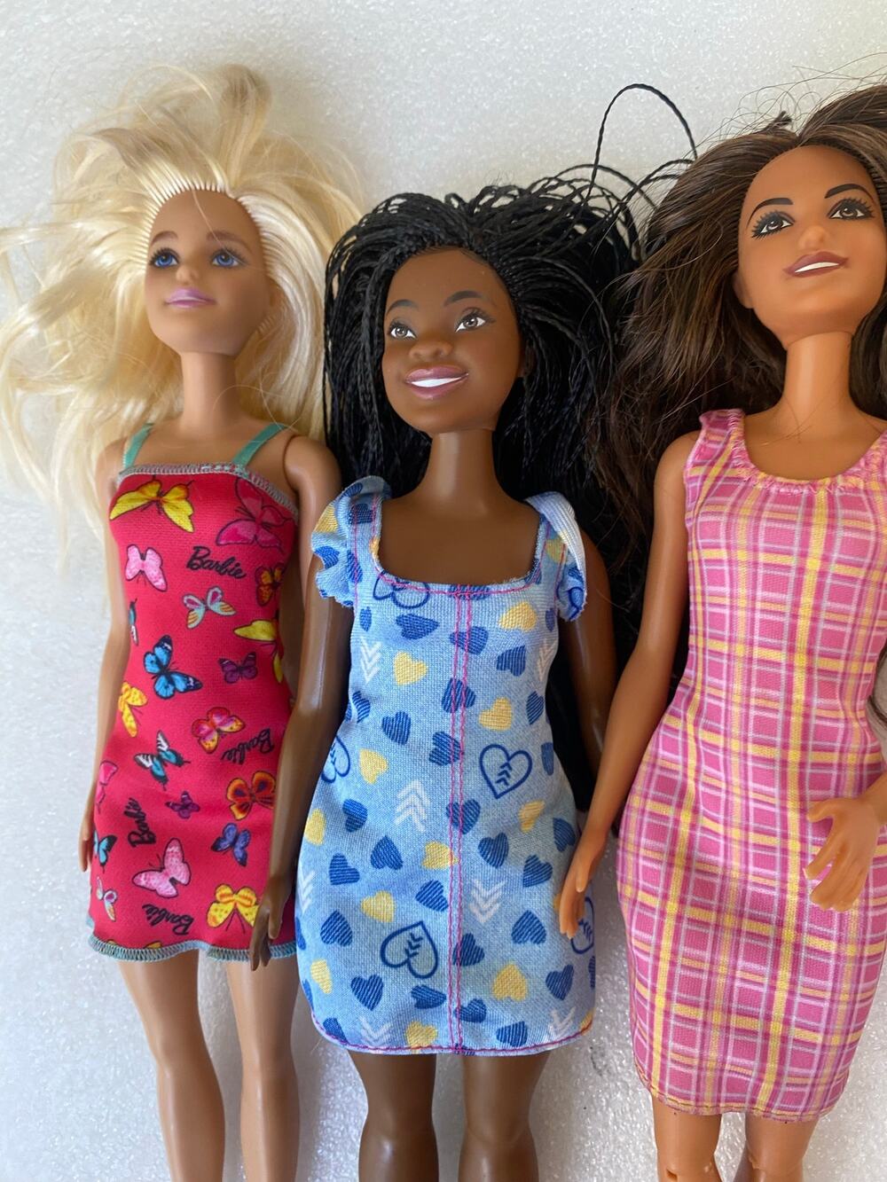 three Mattel Barbie fashion dolls wearing casual printed dresses.